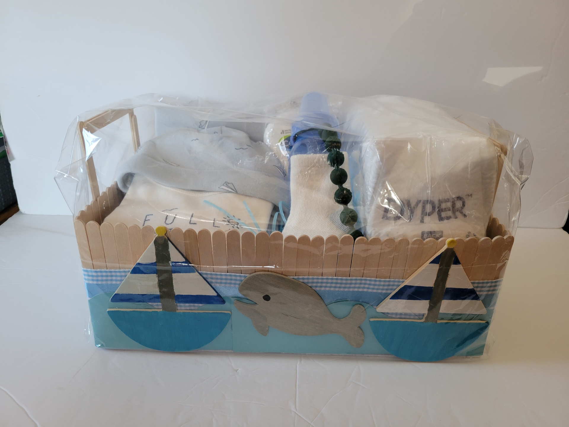 Cardboard craft boat with blue-and-white sail designs and transparent plastic cover