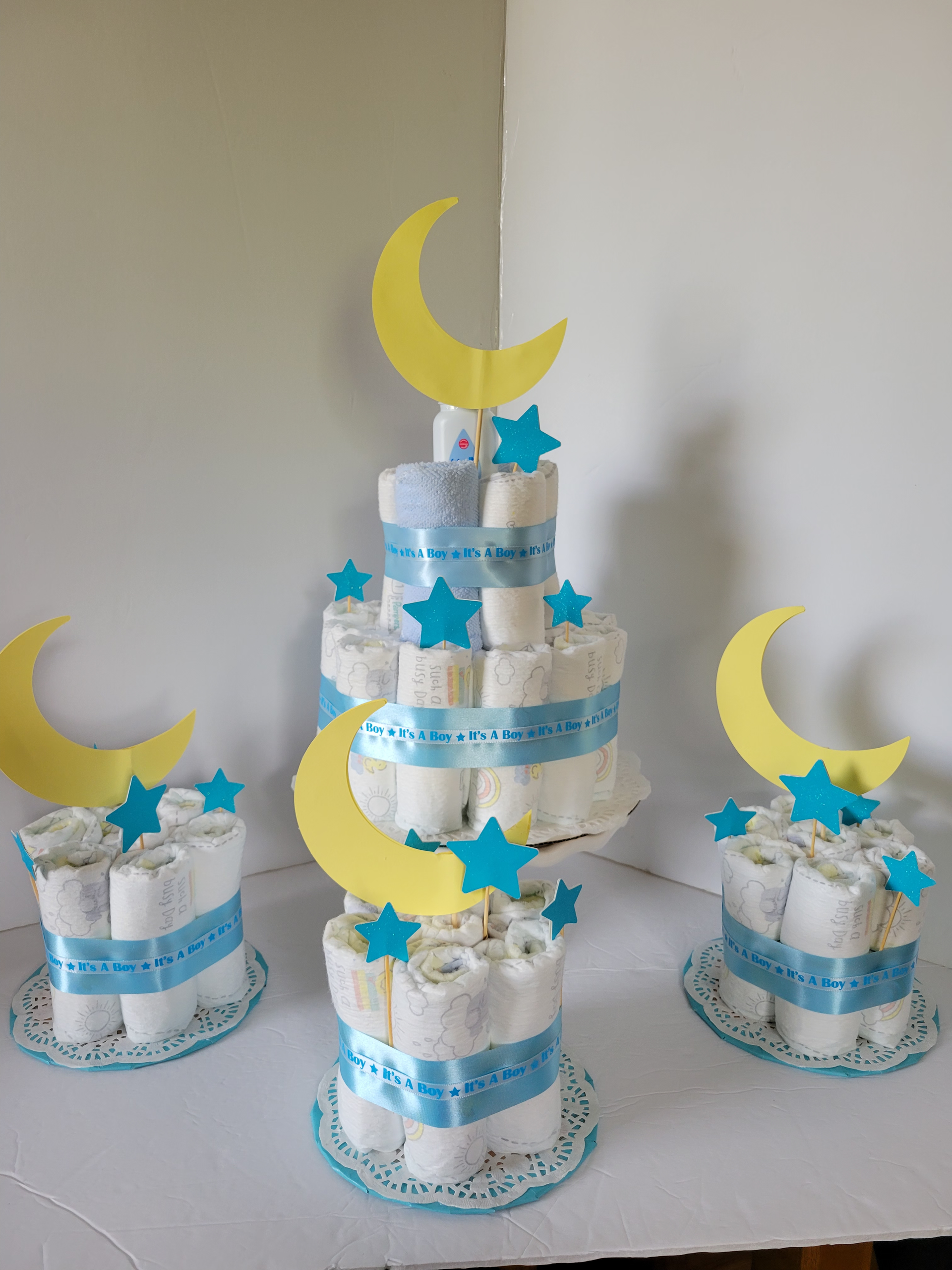Five blue and white tiered cakes with yellow moons and blue stars on a table