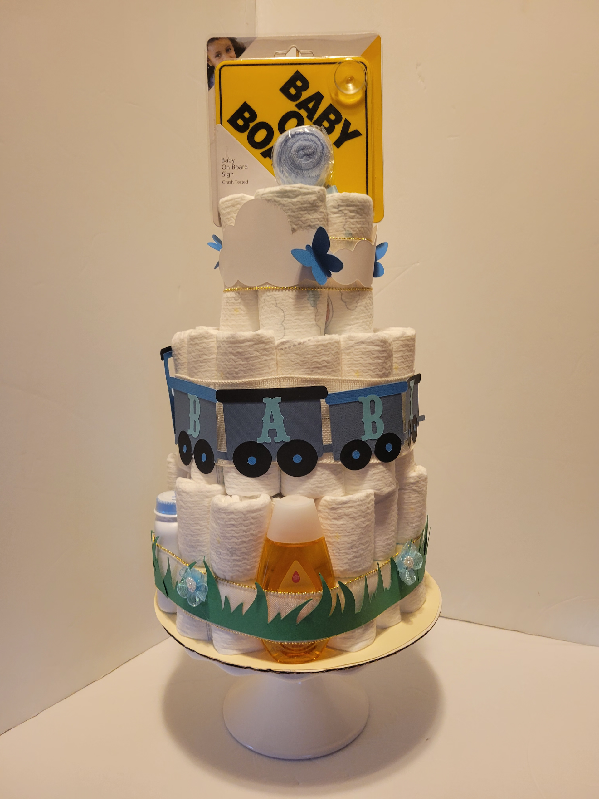 Snowman-themed cake with a blue truck and yellow box topper on a white stand