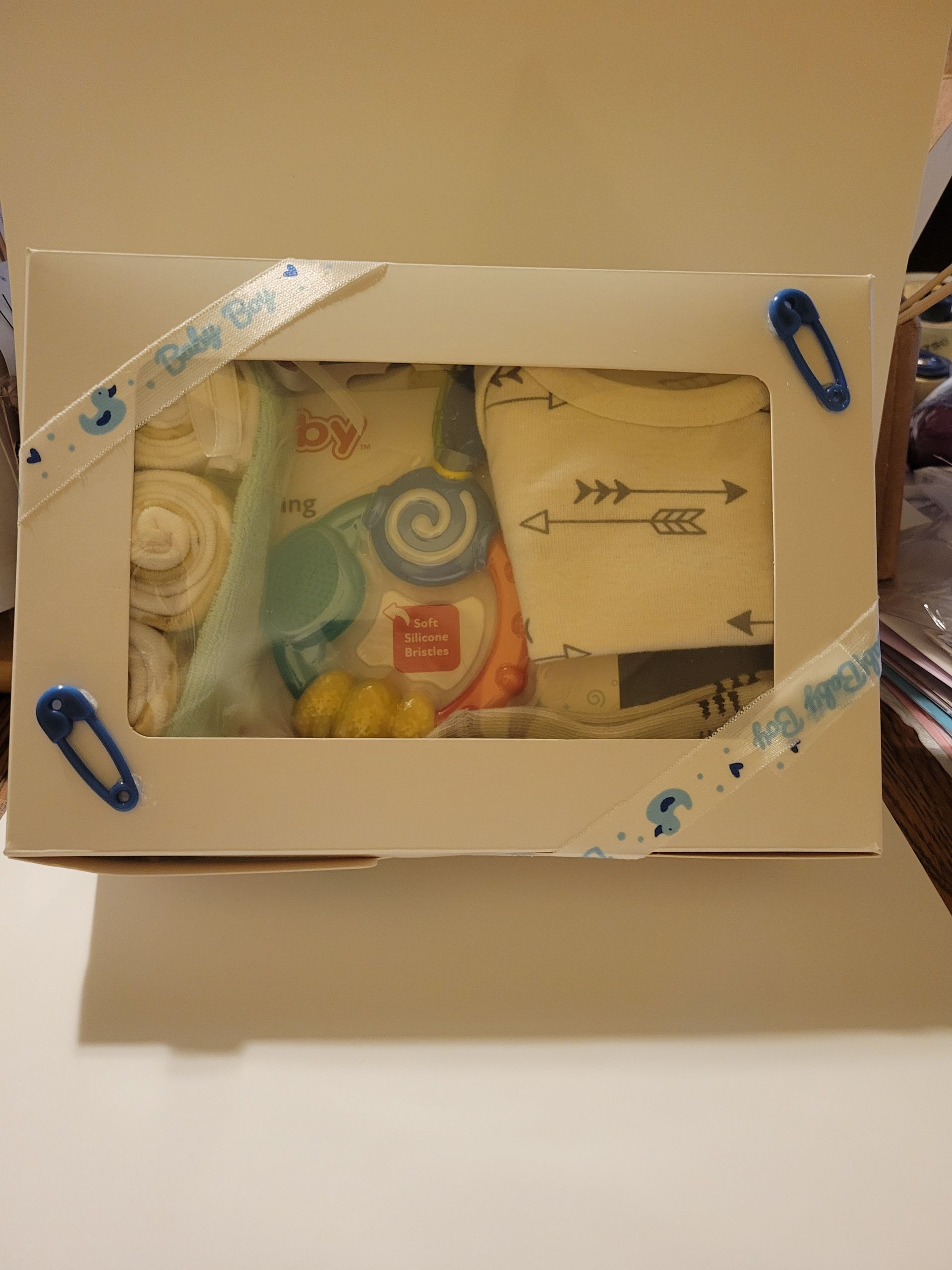 Cardboard box with a clear window showing a colorful wrapped gift and a small card inside.