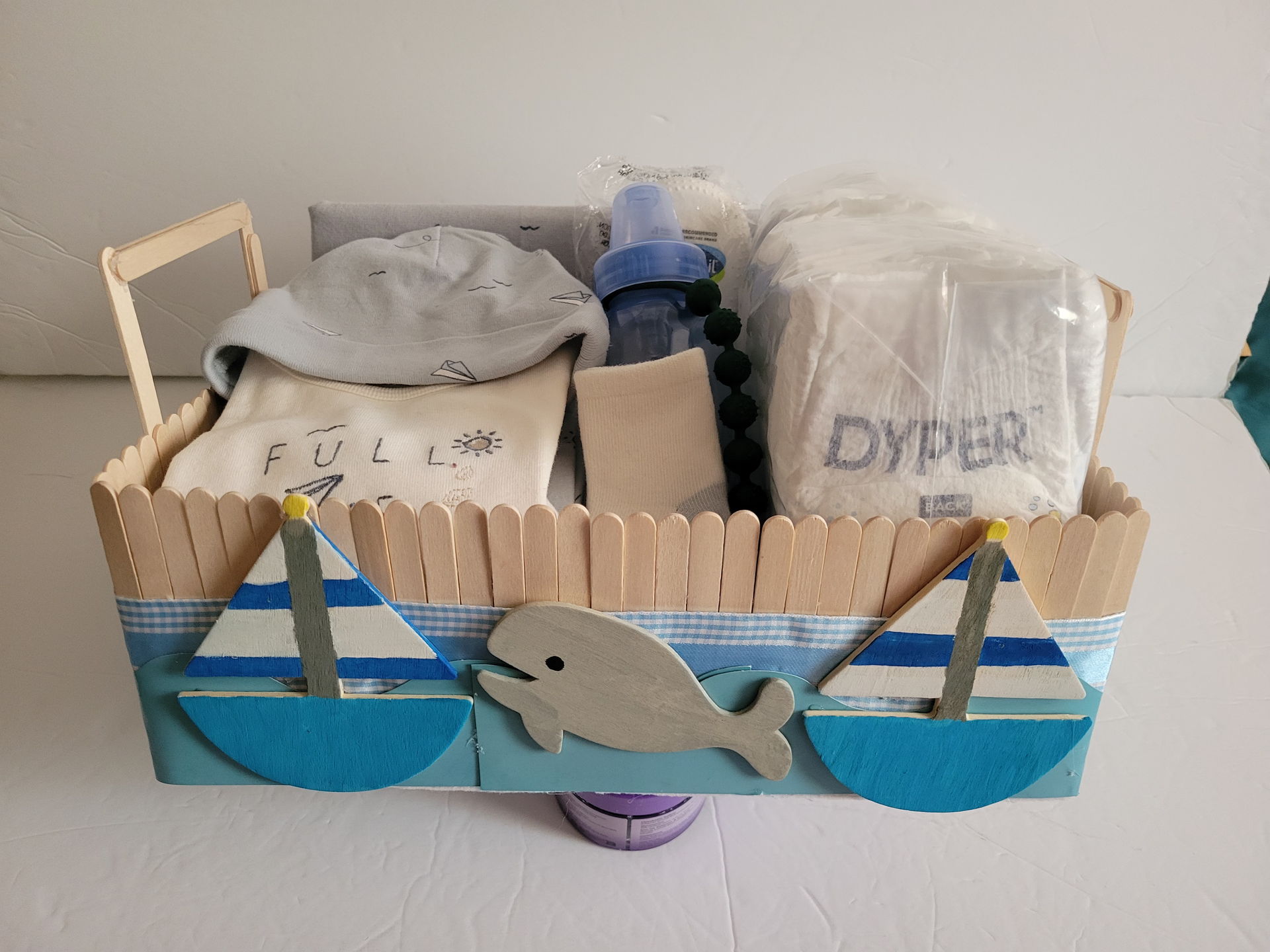 Assorted folded clothing and packaged items laid out on a white bed or table.