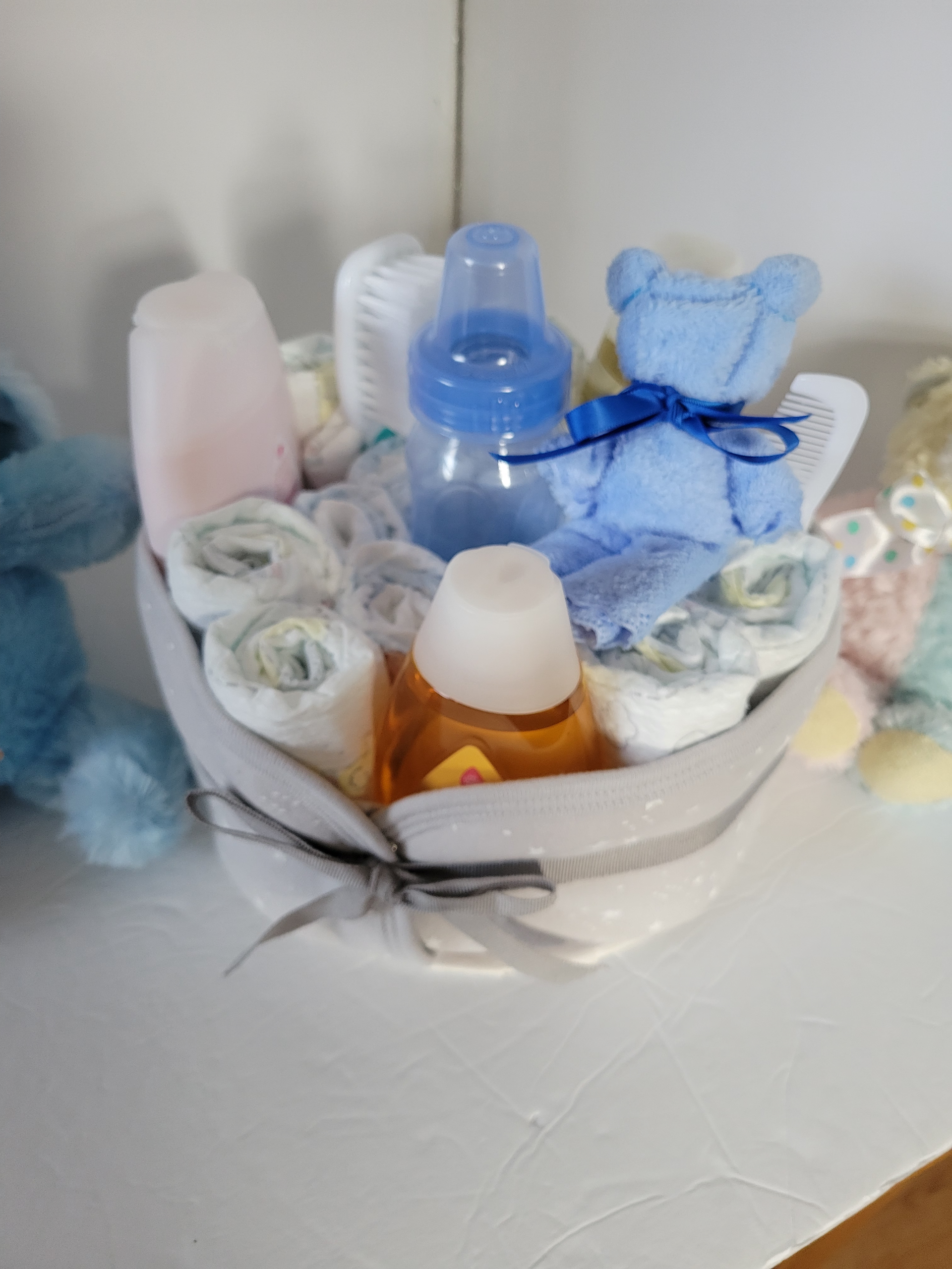 Teddy bears and baby items arranged in a white basket on a shelf