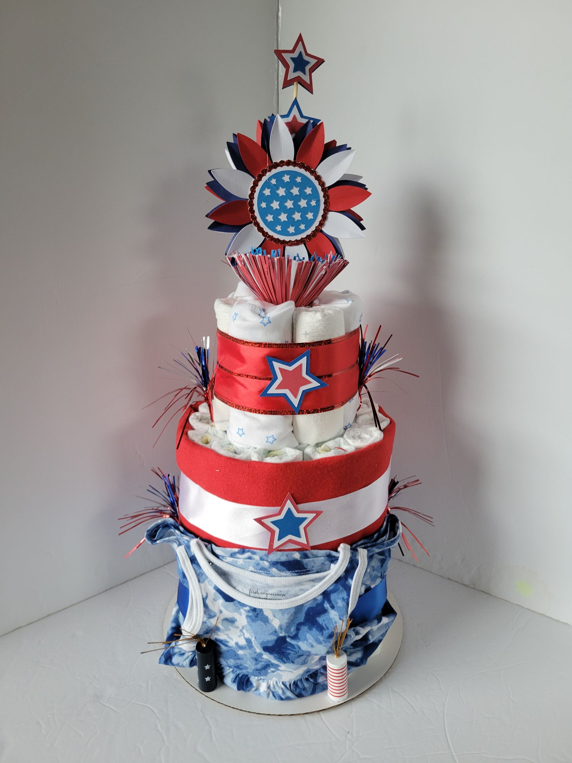 Red, white, and blue decorated tiered cake with a star topper on a plain background