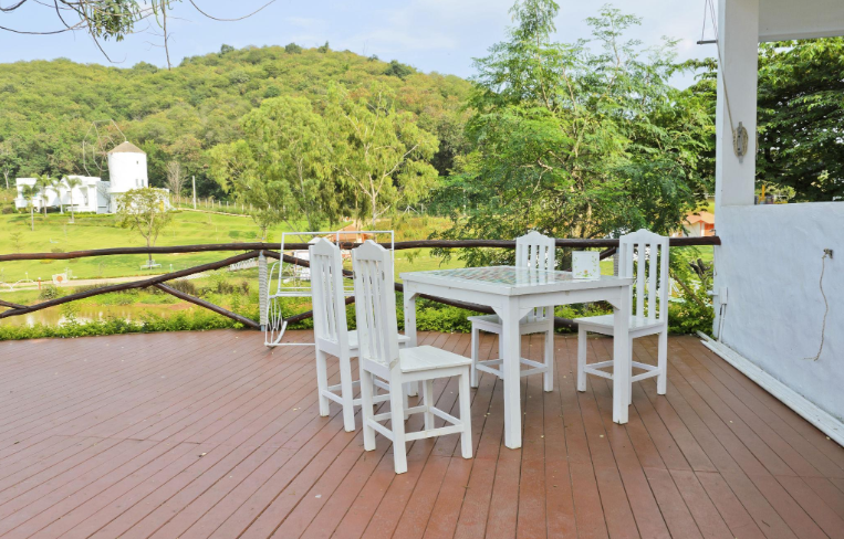 “Covered deck with white outdoor dining furniture, railing, and open scenic yard view by deck builders in Hampton, VA”