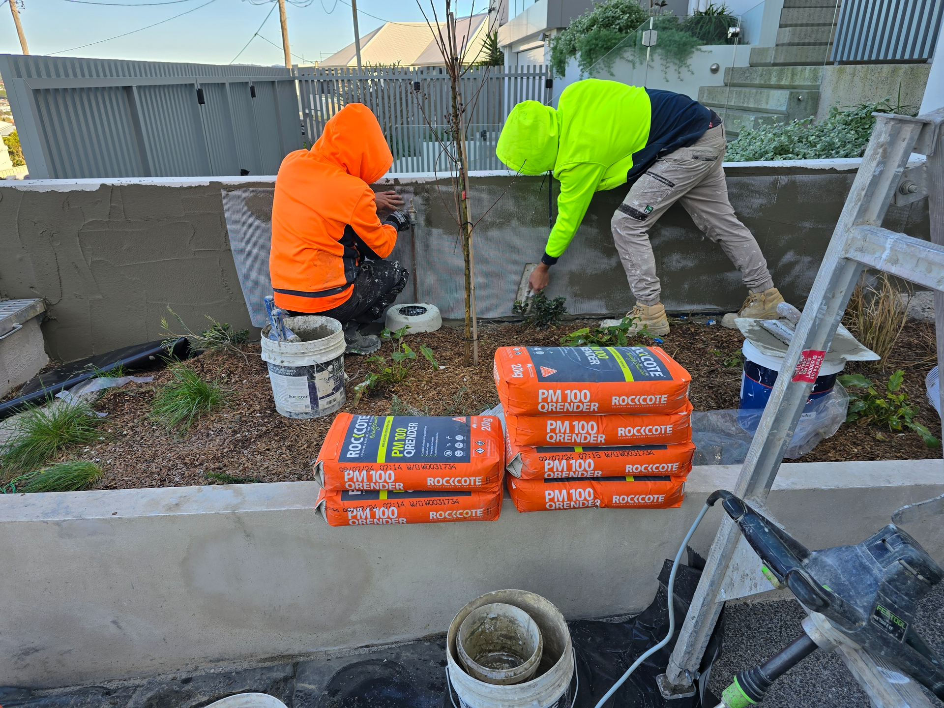 Person rolling white roof coating on a flat rooftop under a blue sky