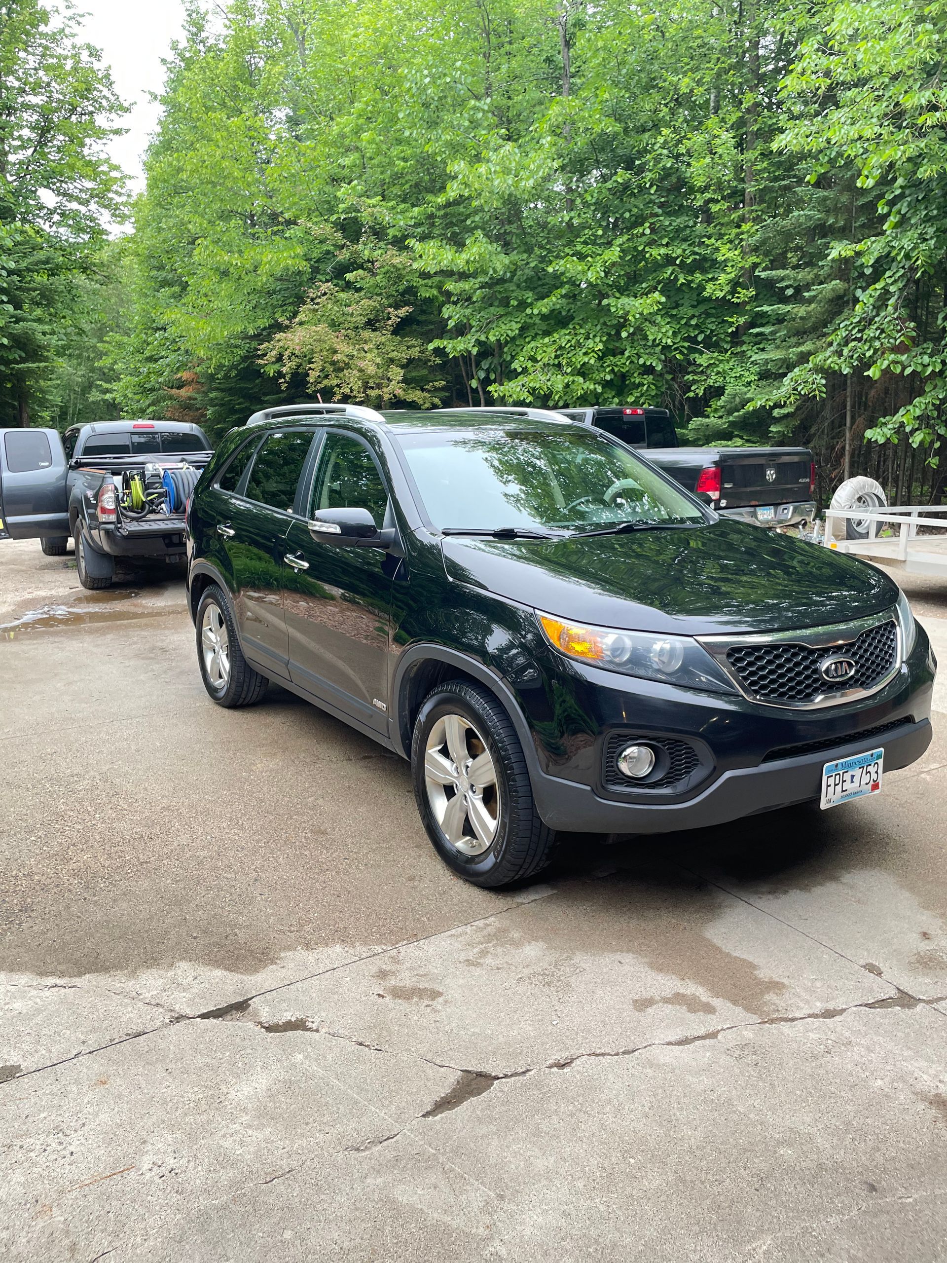 A black suv is parked in a parking lot next to a truck.