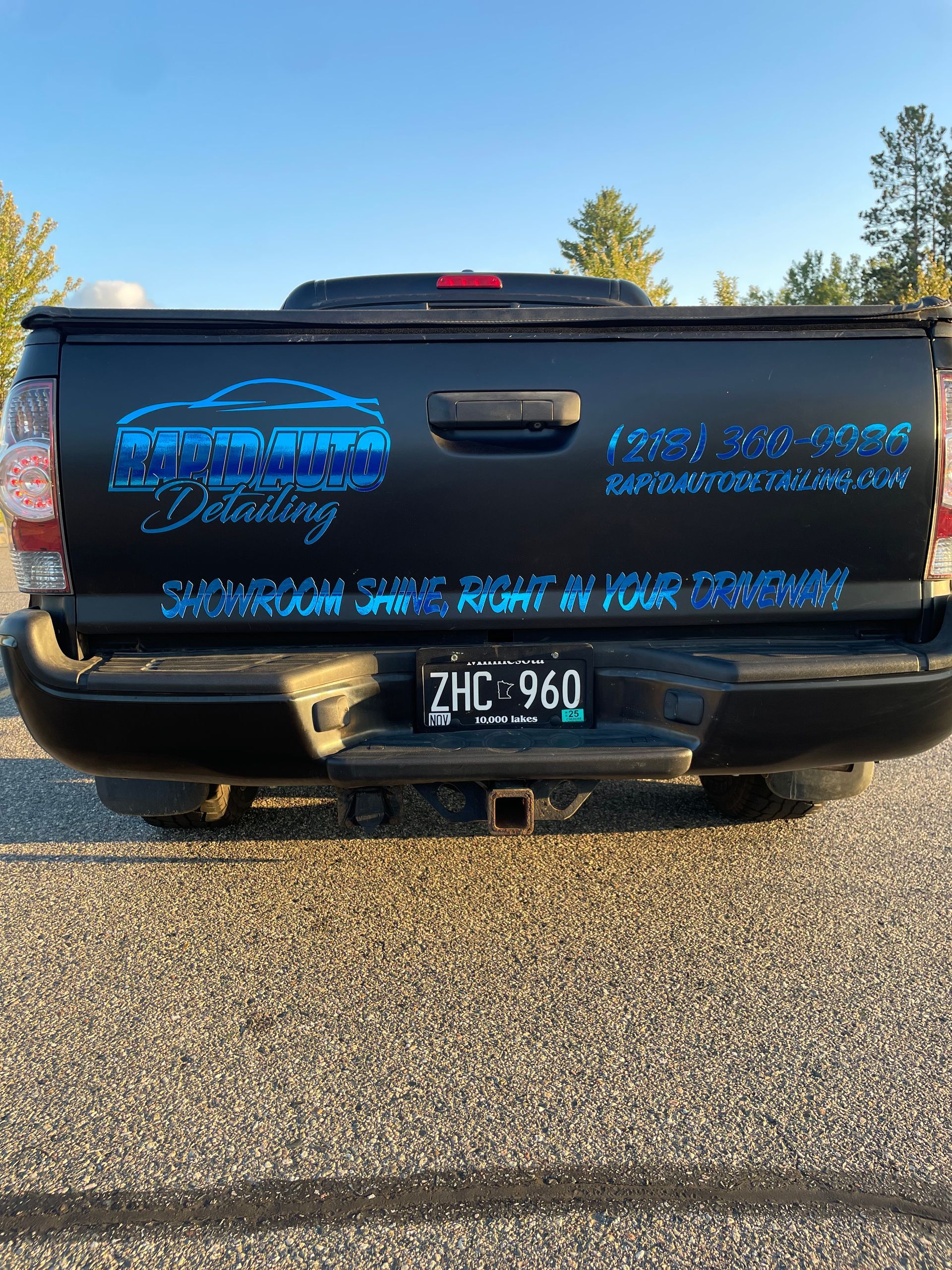 Black truck with blue and silver detailing service logo and phone number on the tailgate.