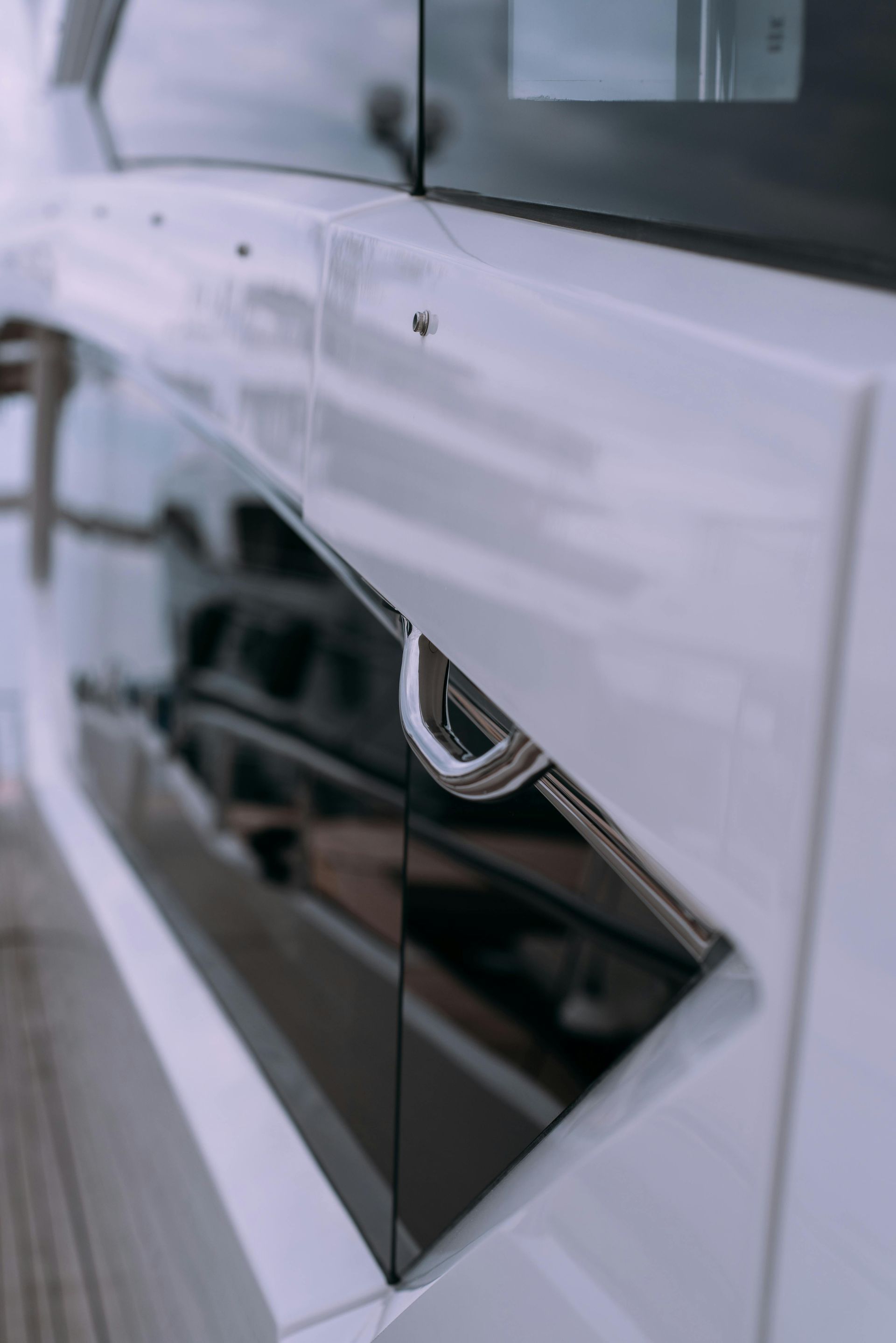Close-up of a car door with a chrome handle and glossy white-and-black paneling