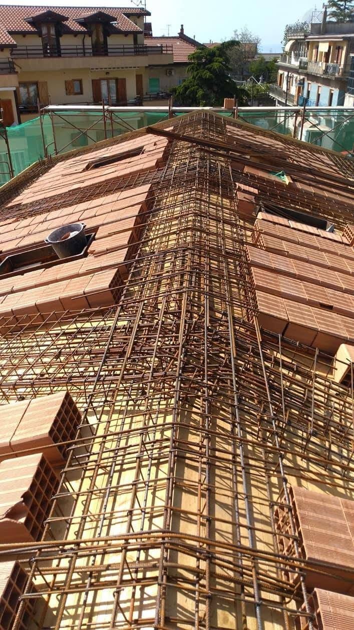 Tetto in costruzione con fitta impalcatura di bambù sopra tetti di tegole rosse in una zona residenziale
