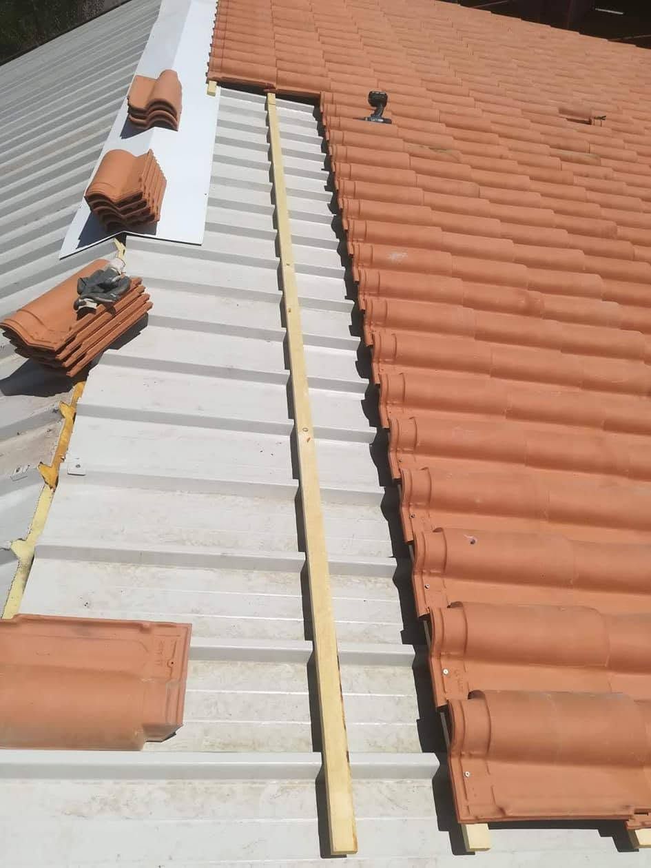 Tetto in riparazione con scala e sottostrato esposto tra le tegole di terracotta rossa