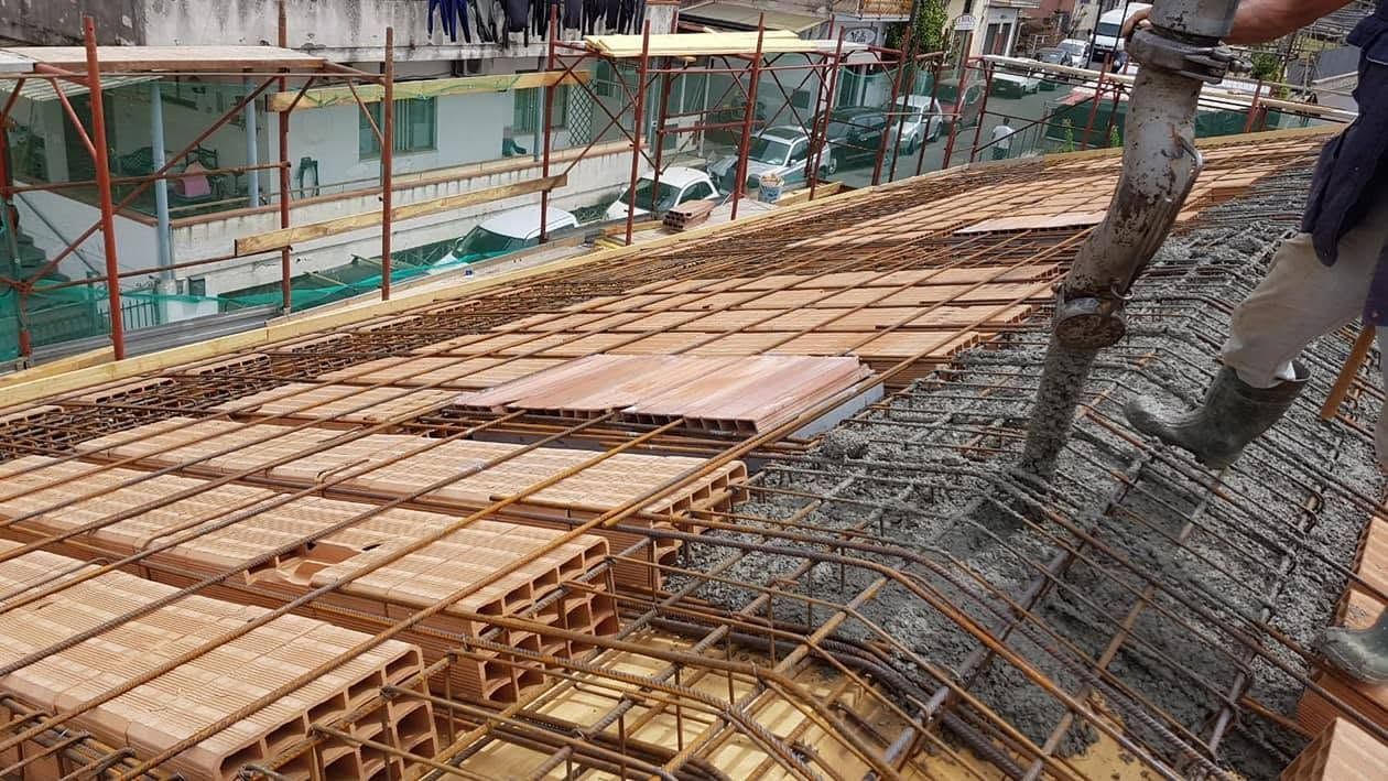 Cantiere edile con armature in ferro e casseforme in legno per la gettata di una soletta in cemento su un tetto.