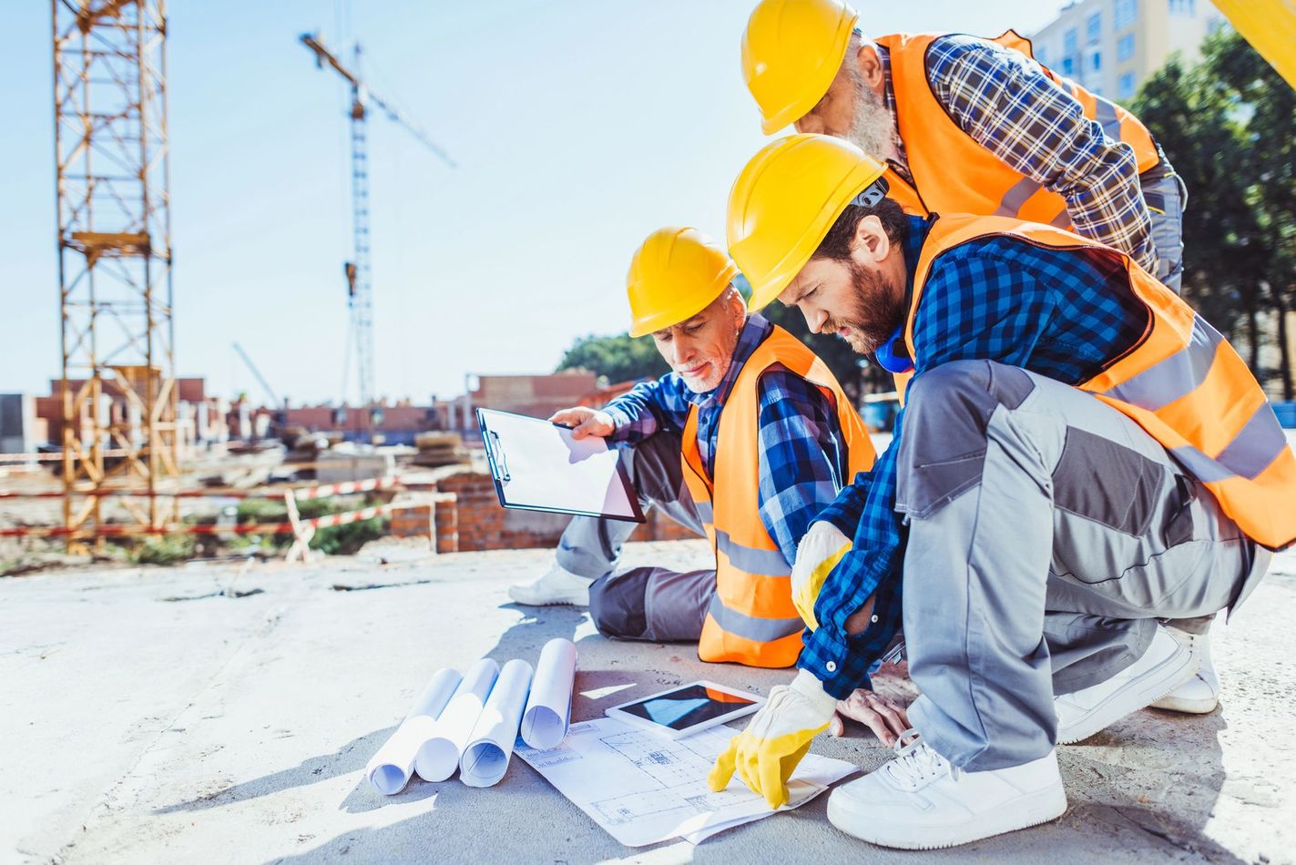 Operai edili con elmetti di sicurezza esaminano i progetti in un cantiere.
