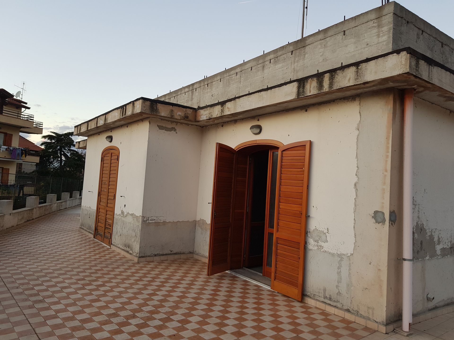 Piccola casa bianca con porte di legno e cortile piastrellato al crepuscolo