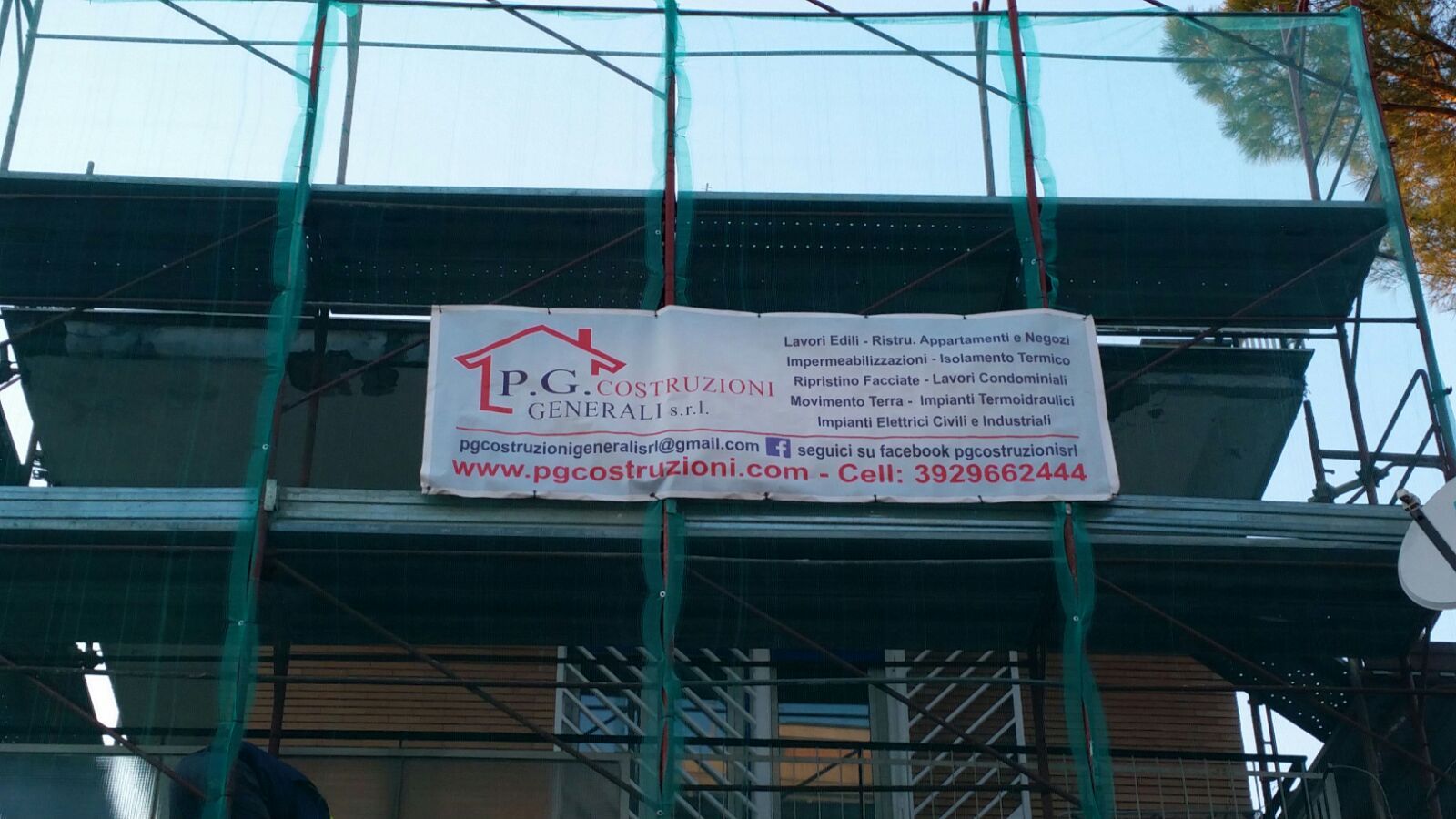 Impalcature intorno a un edificio con un grande striscione bianco con testo rosso e nero sul davanti