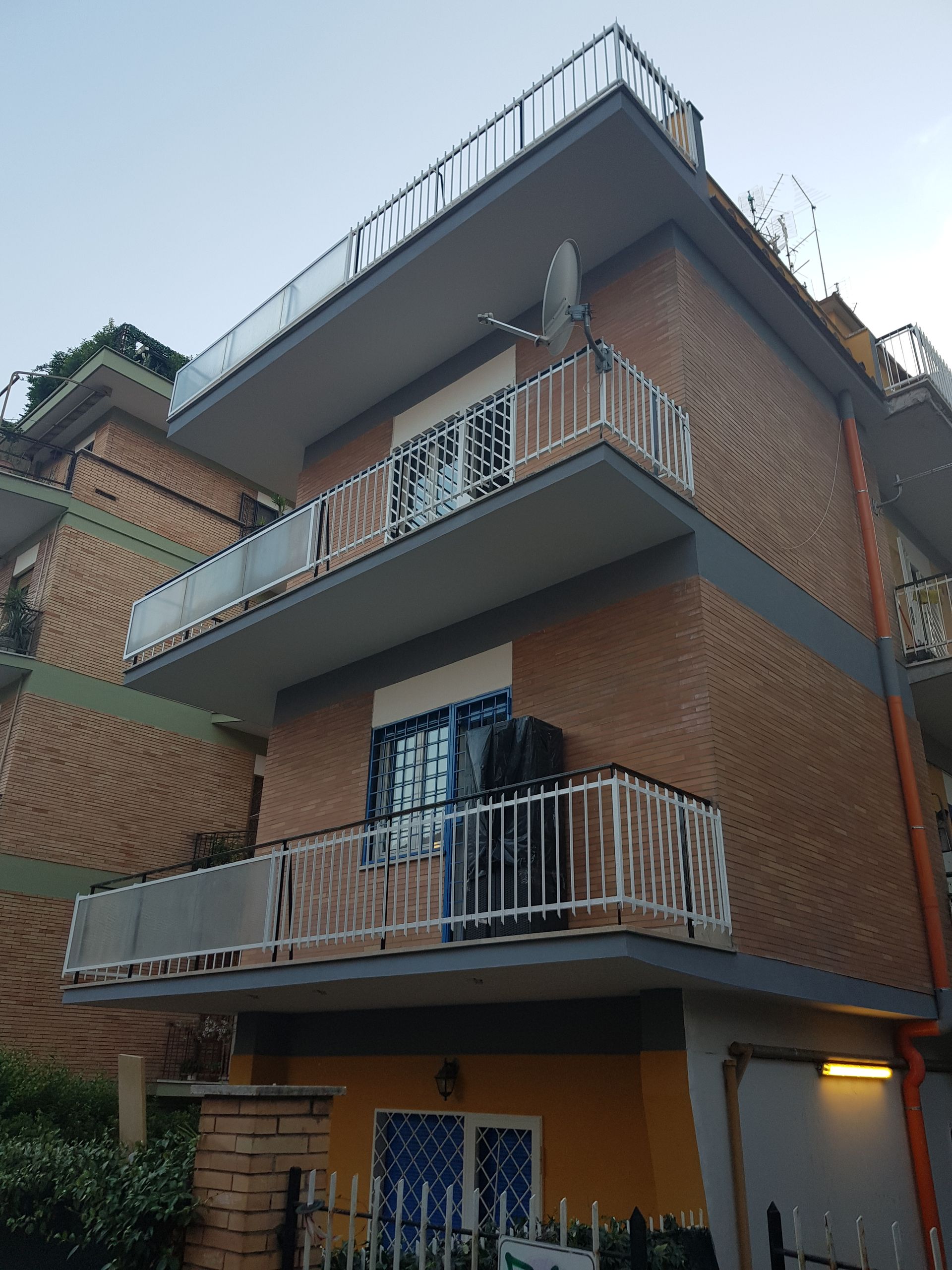 Edificio residenziale di tre piani in mattoni con balconi e ringhiera sul tetto al crepuscolo
