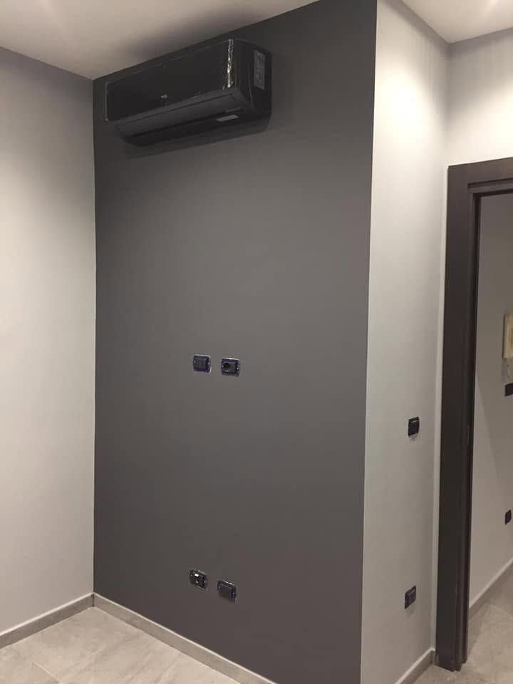 Parete interna con condizionatore d'aria a incasso e prese elettriche in un corridoio.