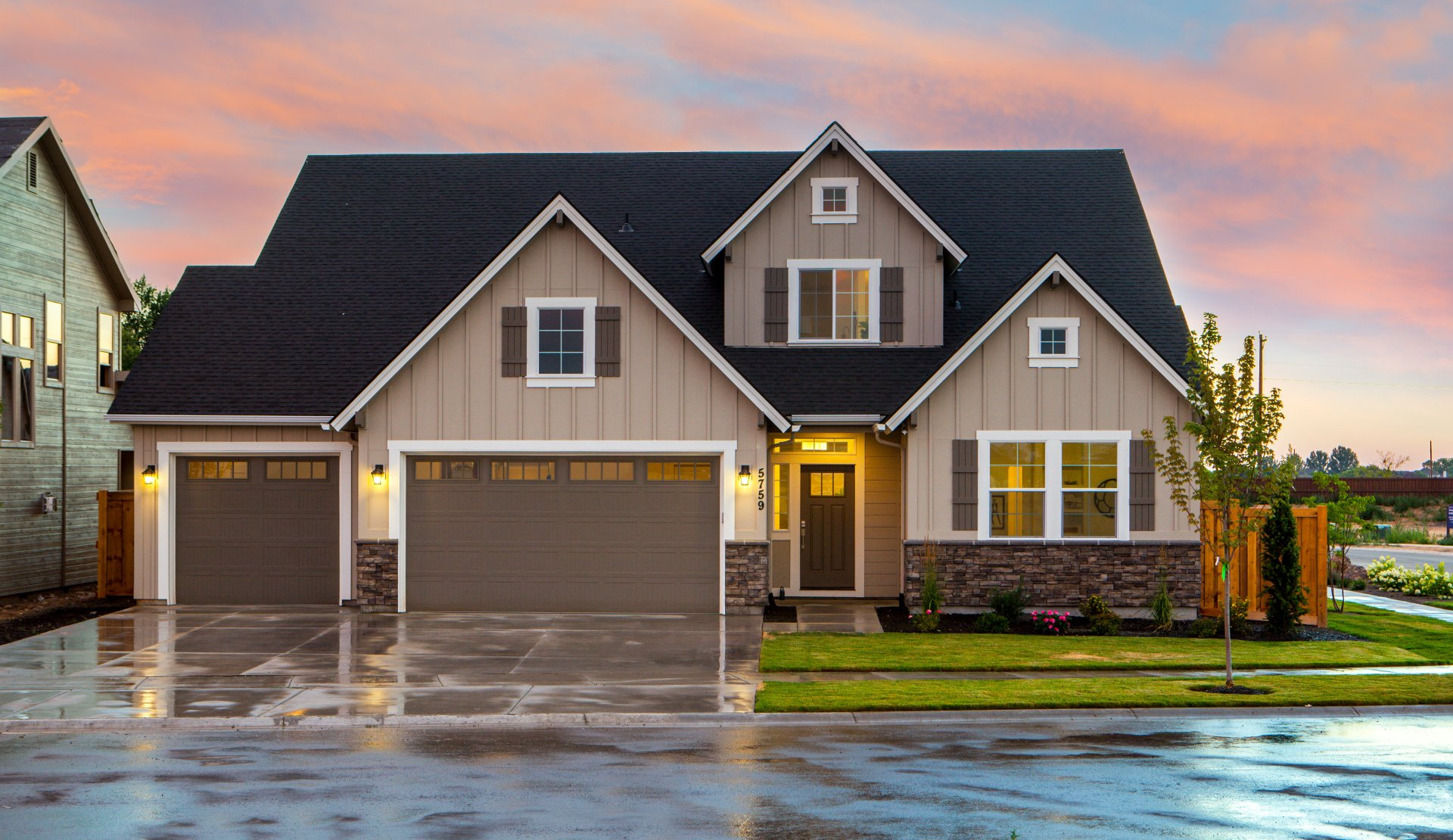 a house with two garage doors and a sunset in the background