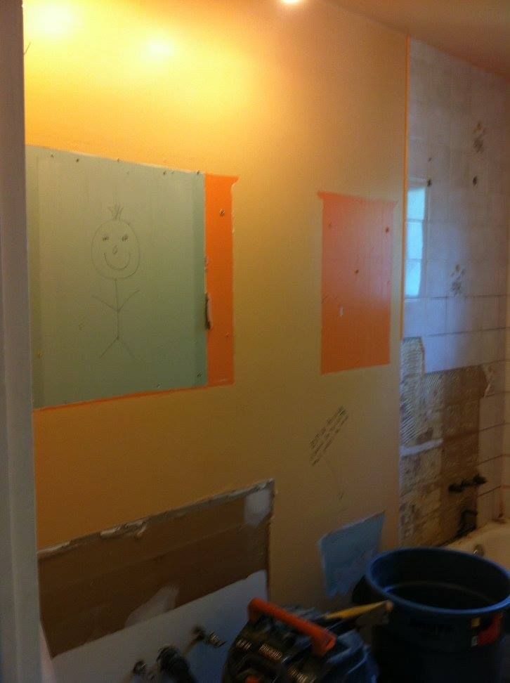 Une salle de bain en construction avec un seau d'eau et un aspirateur.