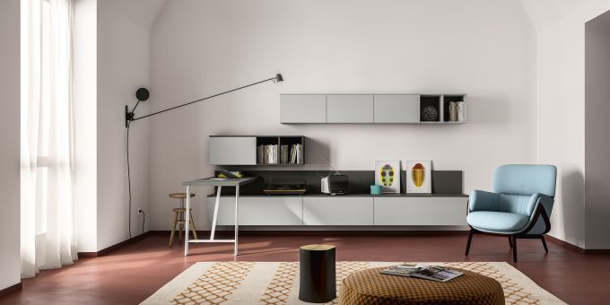 Un soggiorno contemporaneo caratterizzato da una libreria a muro, una poltrona azzurra e un pavimento marrone scuro.