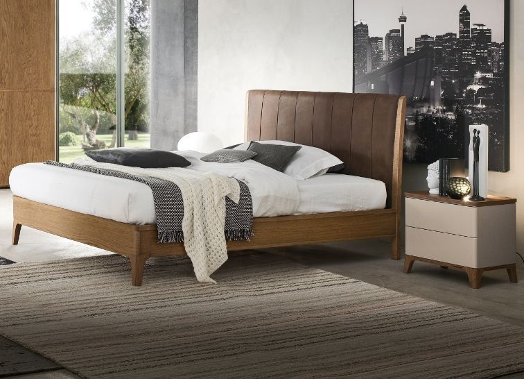 Una camera da letto moderna con un letto con struttura in legno, testiera alta e pannellata e comodino di colore chiaro su un tappeto.