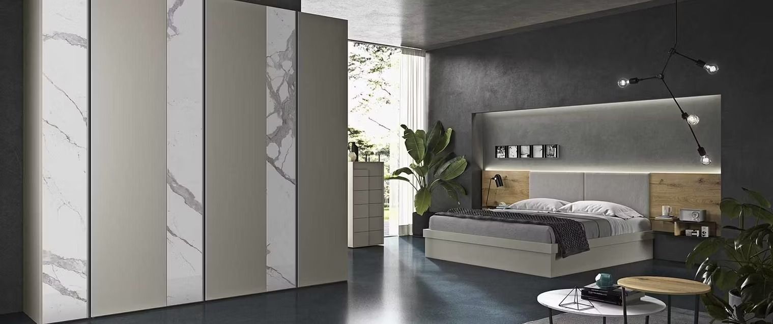 Una camera da letto moderna caratterizzata da un ampio armadio a pannelli multipli con dettagli in marmo e un letto con testiera in legno integrata.