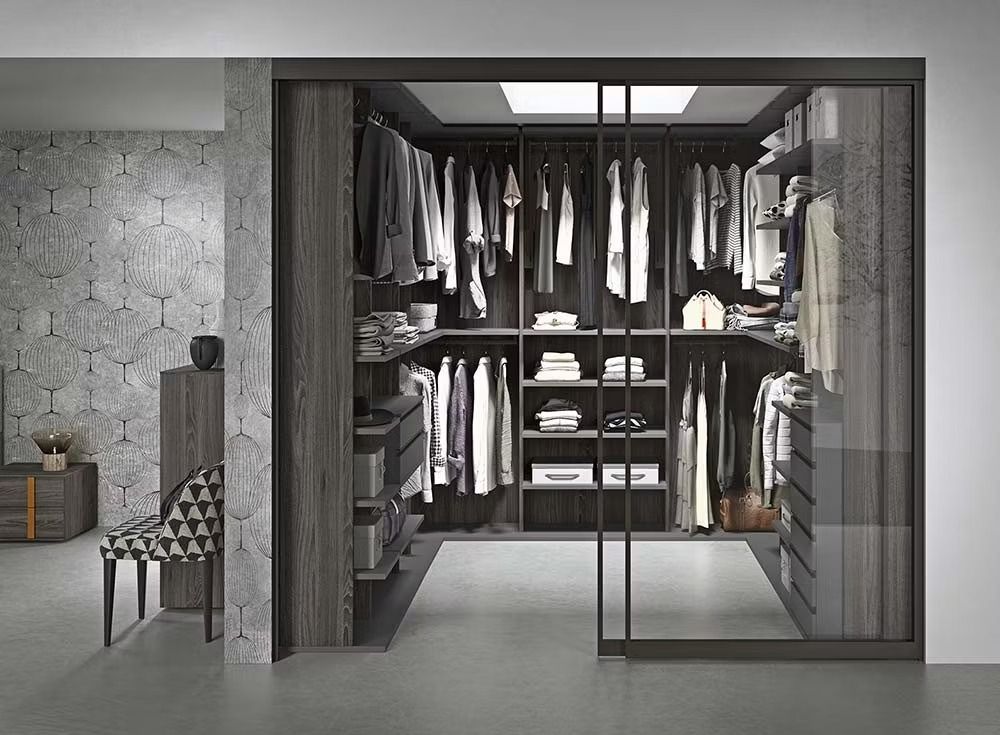 Una moderna cabina armadio con ripiani in legno scuro, appendiabiti e ante scorrevoli in vetro, in una stanza con pareti decorate.