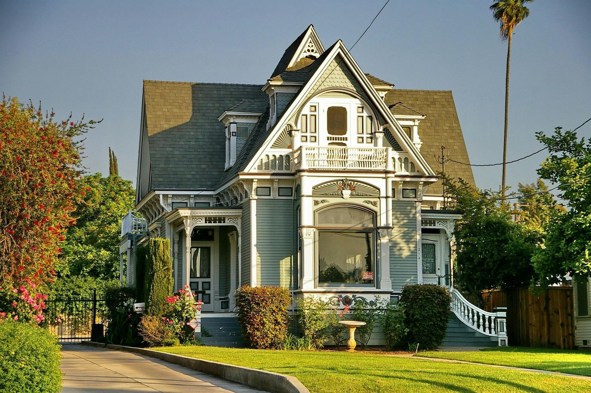 Victorian-style house with gray siding, white trim, and a manicured lawn on a sunny in Central PA