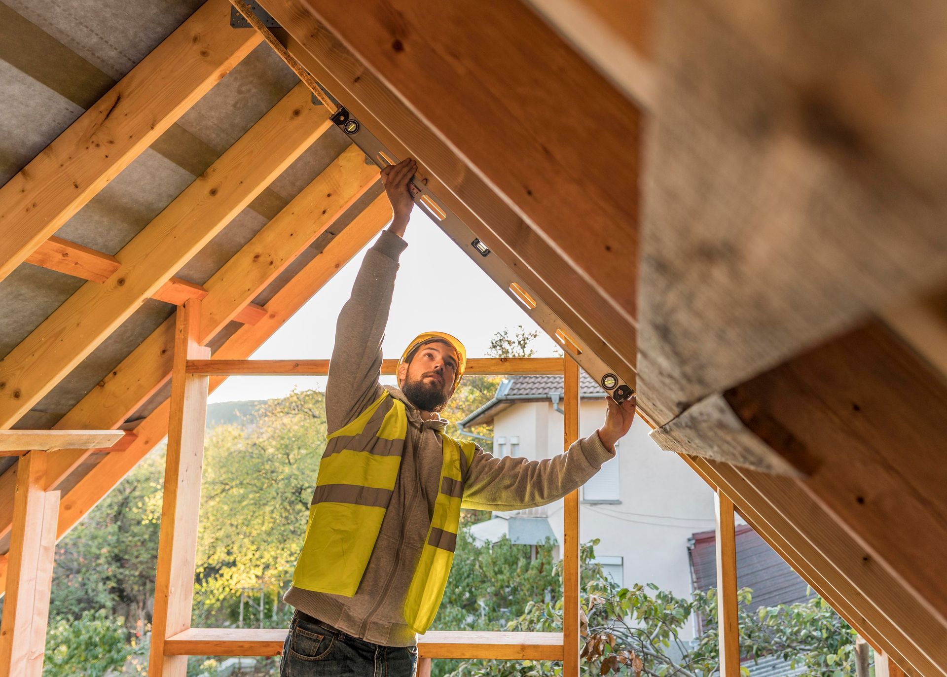 Worker in a safety vest measuring roof framing inside a house under construction in Central PA