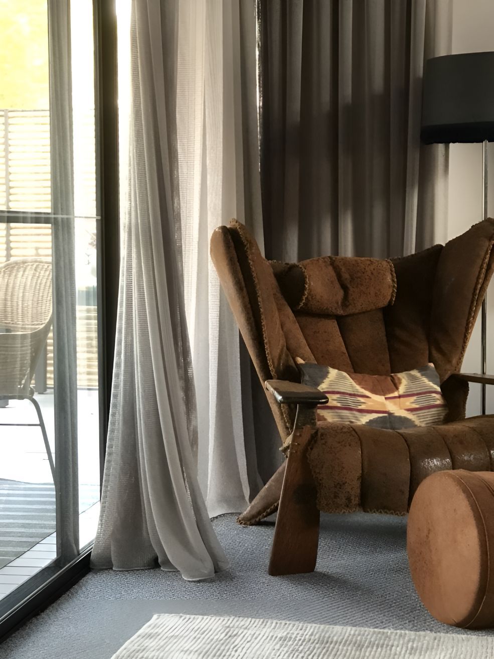 A Chair is Sitting in a Living Room Next to a Sliding Glass Door — Newcastle Curtains And Blinds In Warners Bay, NSW