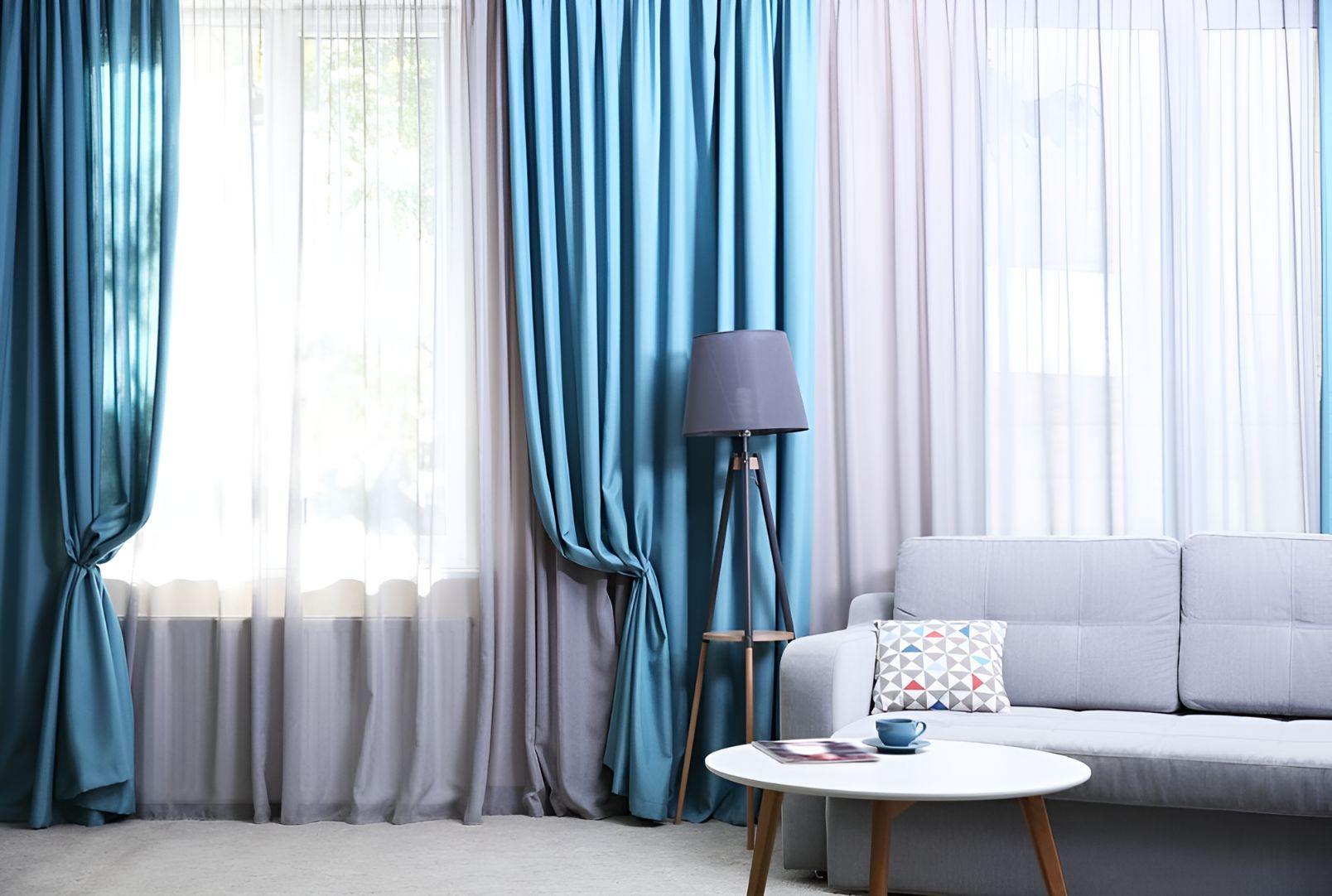 A Living Room With a Couch, Table, Lamp and Blue Curtains — Newcastle Curtains And Blinds In Lambton, NSW