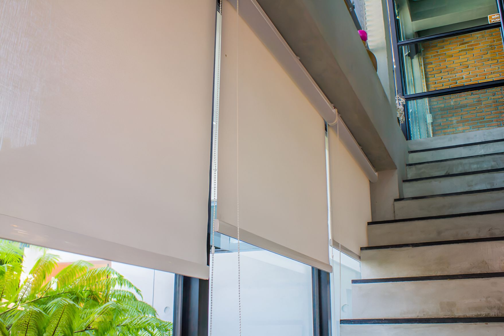 A Pair of Roller Blinds Hanging on a Window Next to a Set of Stairs — Newcastle Curtains And Blinds In Warners Bay, NSW