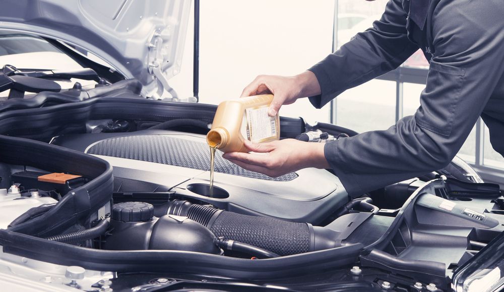 Person Pouring Oil Into a Car Engine — North Queensland Independant Fuel Services in Mackay, QLD