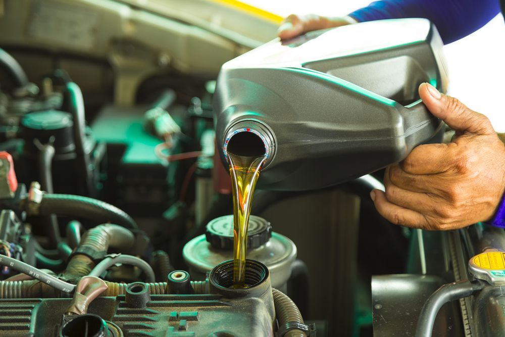 A Person is Pouring Oil Into a Car Engine — North Queensland Independant Fuel Services in Slade Point, QLD