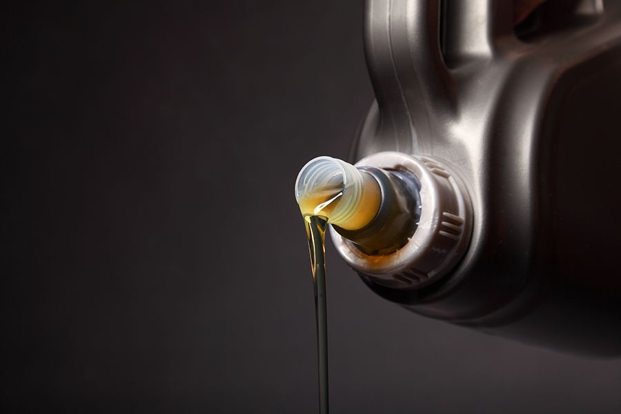 A Bottle of Oil is Being Poured Into a Car Engine — North Queensland Independant Fuel Services in Slade Point, QLD