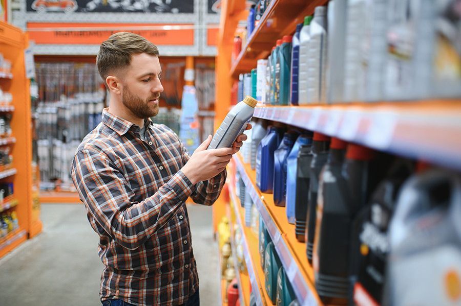 A Man is Looking at a Bottle of Oil in a Store — North Queensland Independant Fuel Services in Slade Point, QLD