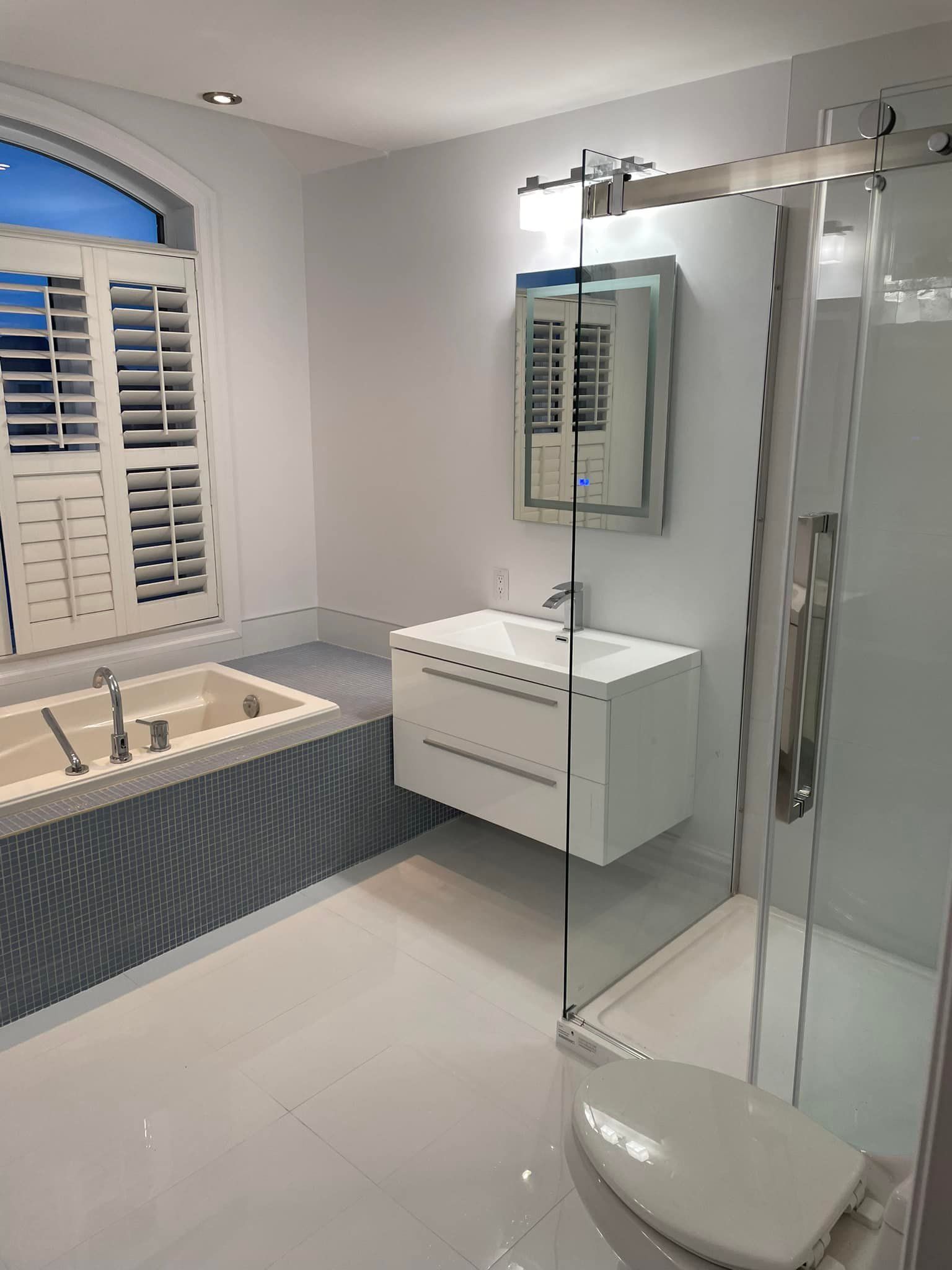 Salle de bains moderne avec murs blancs, meuble-lavabo suspendu, douche et baignoire.