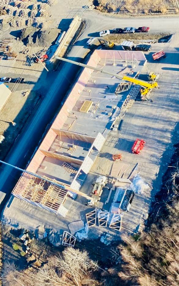 Chantier de construction avec une structure partiellement construite, de l'asphalte et du matériel.