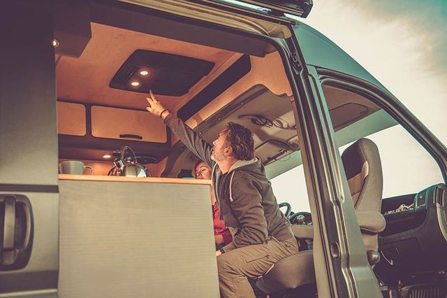Person reaching up inside a van with a raised roof and warm interior lighting