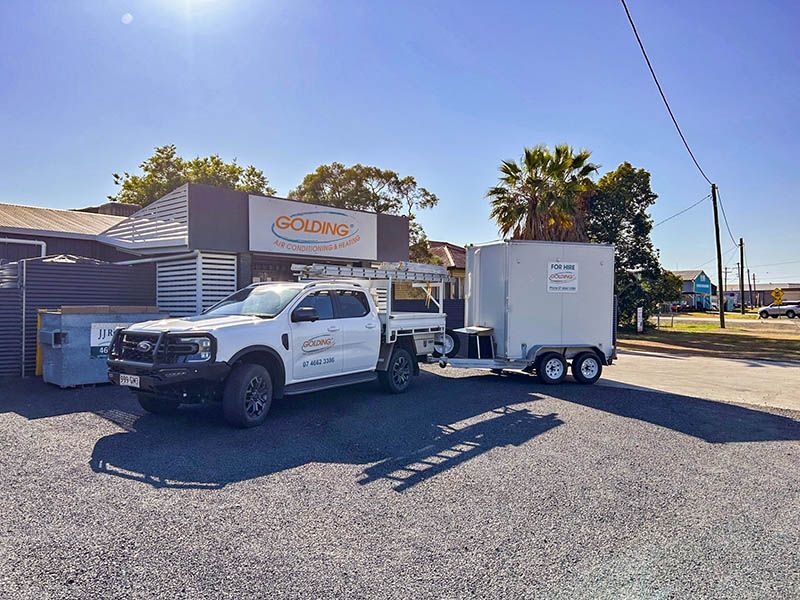 White utility truck towing a white trailer parked outside a Cigna office on a sunny street