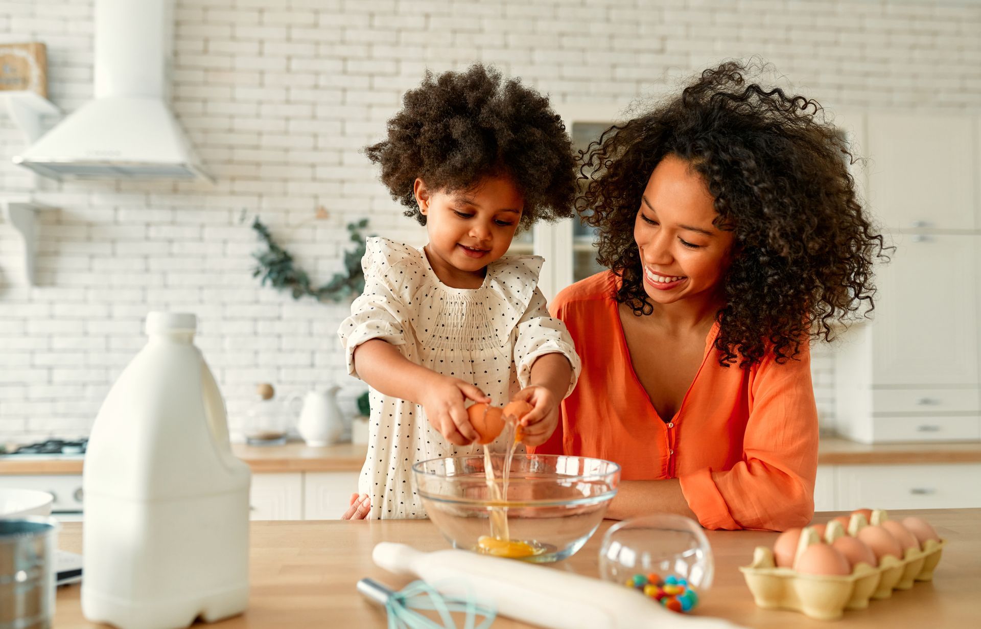 A mother and daughter are baking in the kitchen. They are smiling.