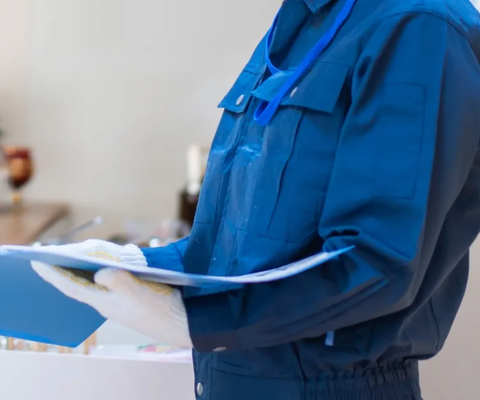 Person in blue uniform holding a clipboard and pen in a clinical setting