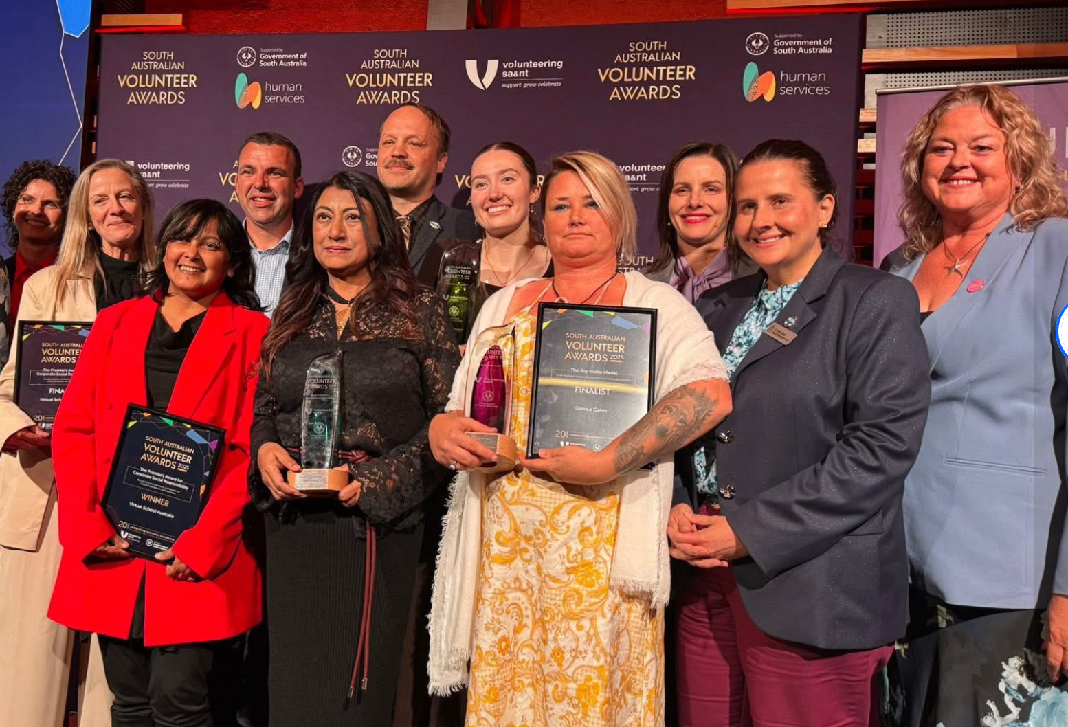 Award recipients posing onstage, holding plaques and certificates at a recognition ceremony