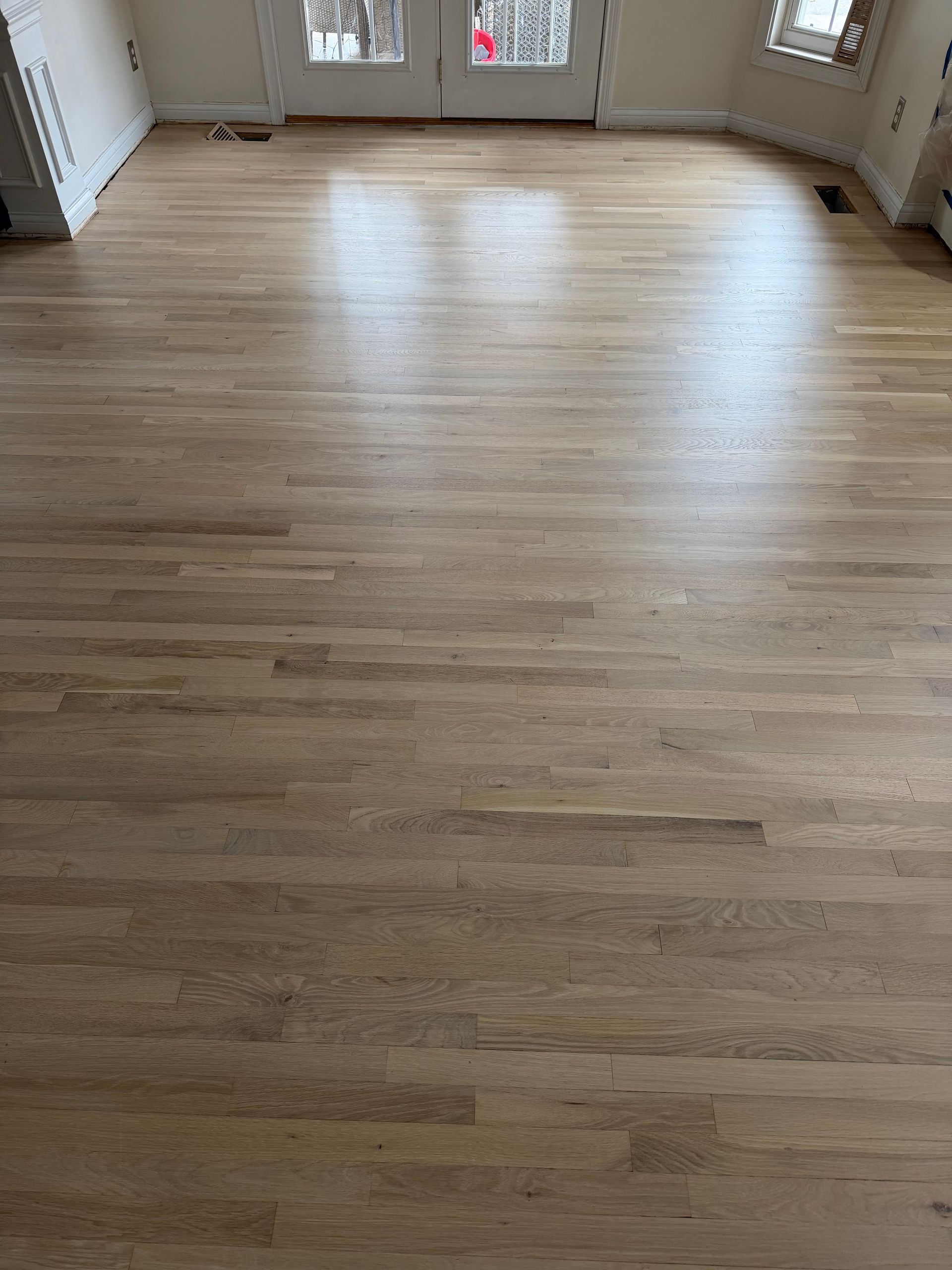 Person wearing gloves installing wooden floorboards with adhesive.