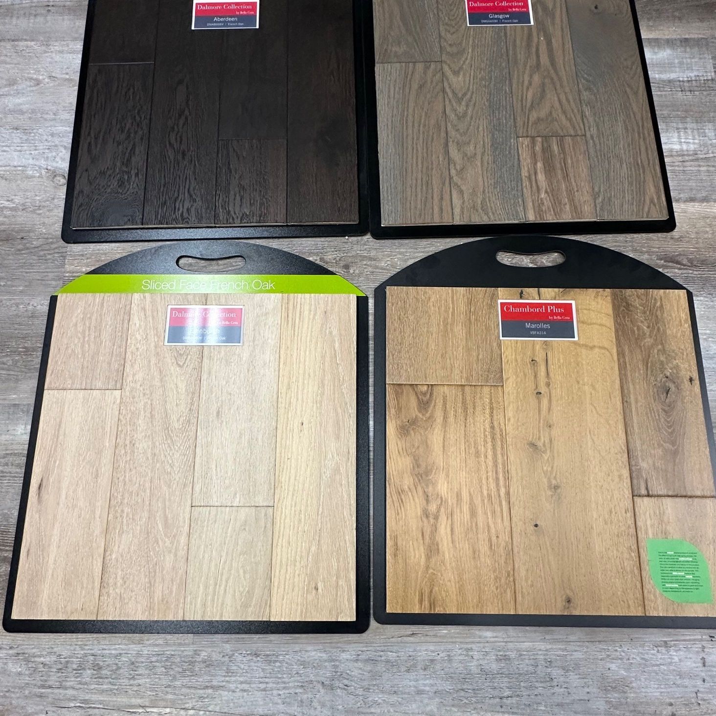 Four hardwood flooring samples displayed; dark brown, gray, light tan, and golden brown colors.