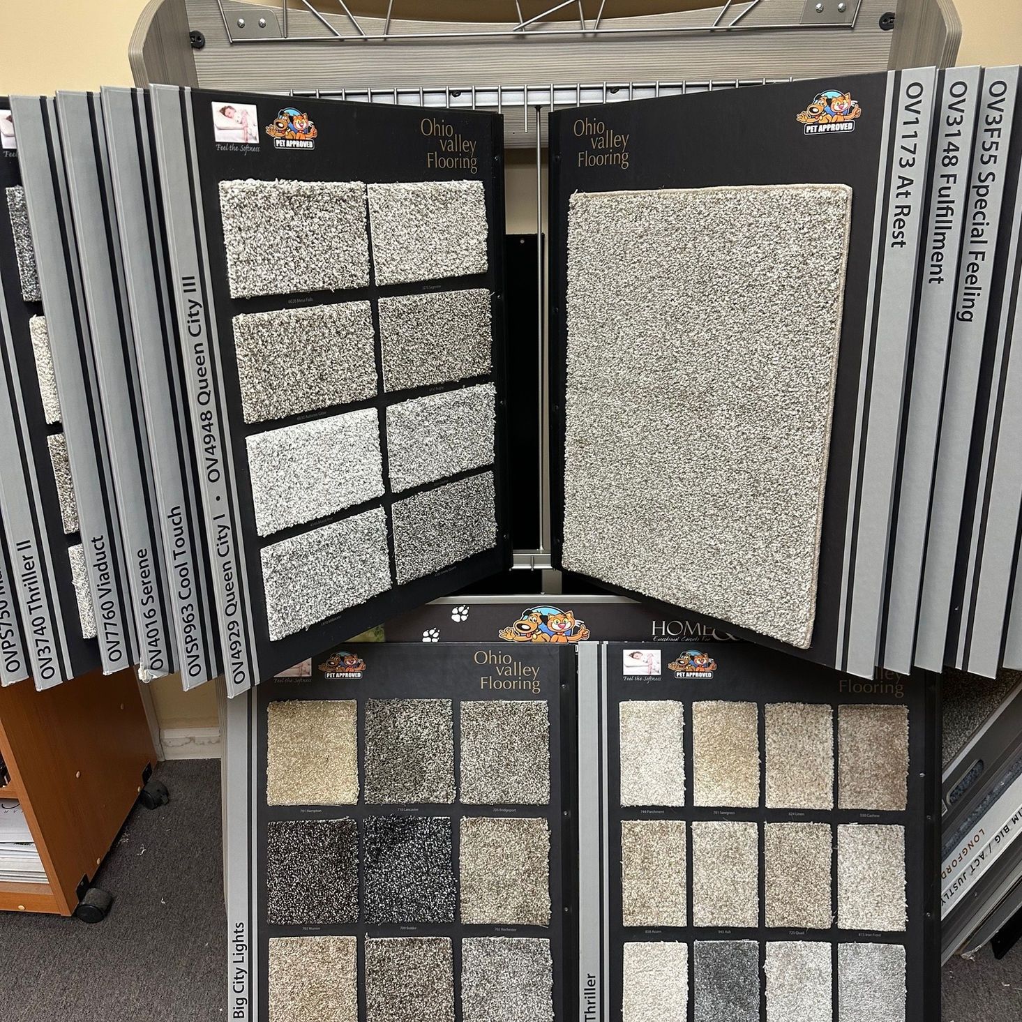 Carpet samples displayed on racks in a showroom, showing various colors and textures for flooring.