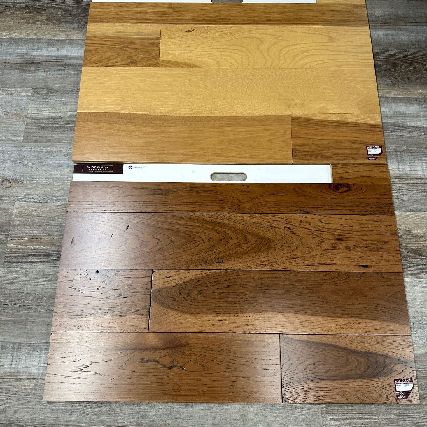 Wooden floor samples in shades of light brown to dark brown, arranged on a gray surface.