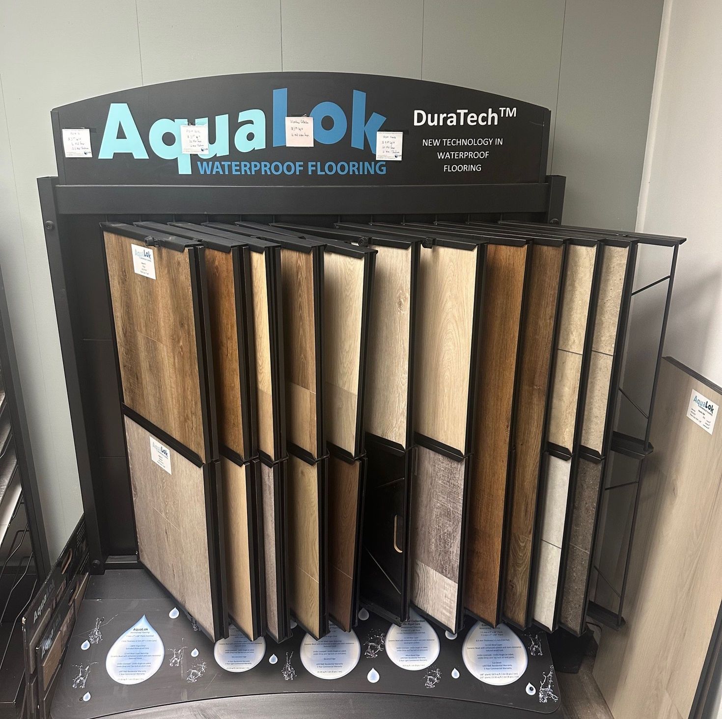 Display of Aqualok waterproof flooring samples in various wood tones.