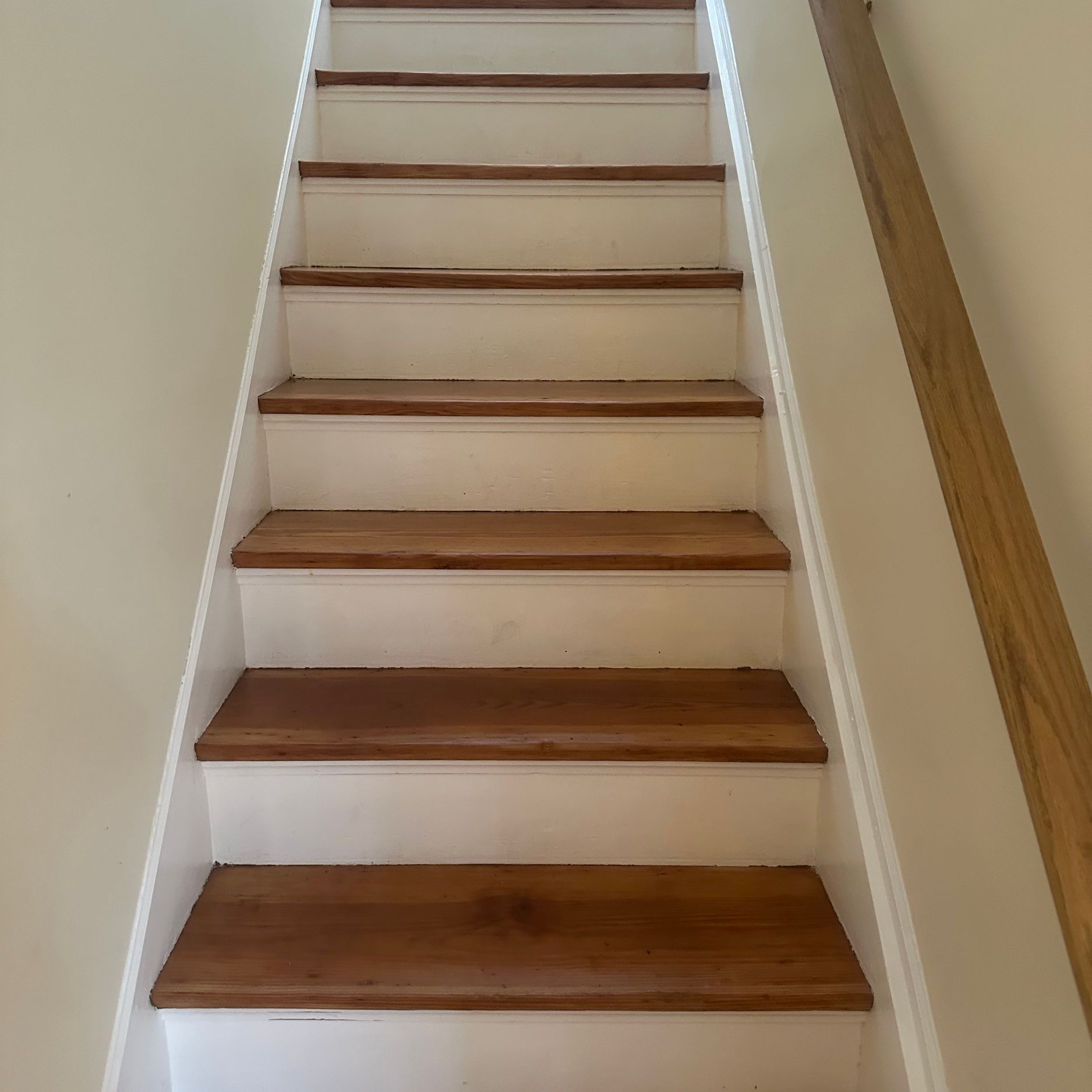 Wooden staircase with white risers and brown treads, viewed from below.