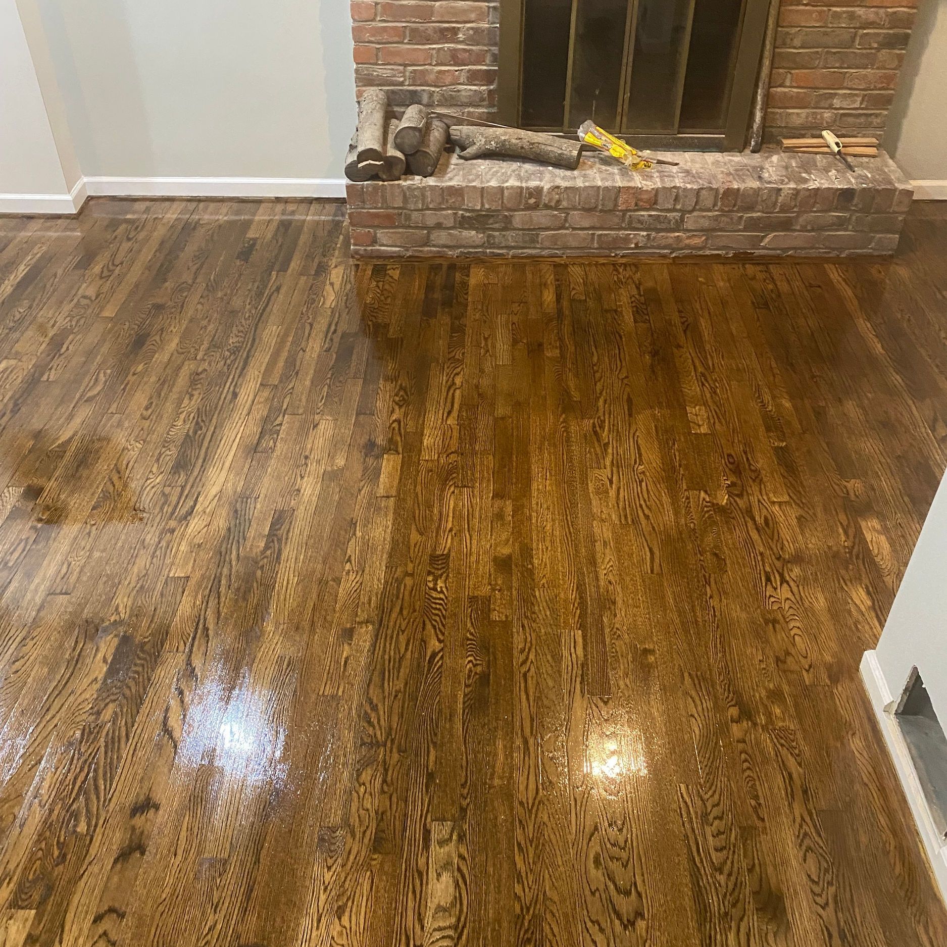 Newly refinished dark stained hardwood floor with fireplace in the background.
