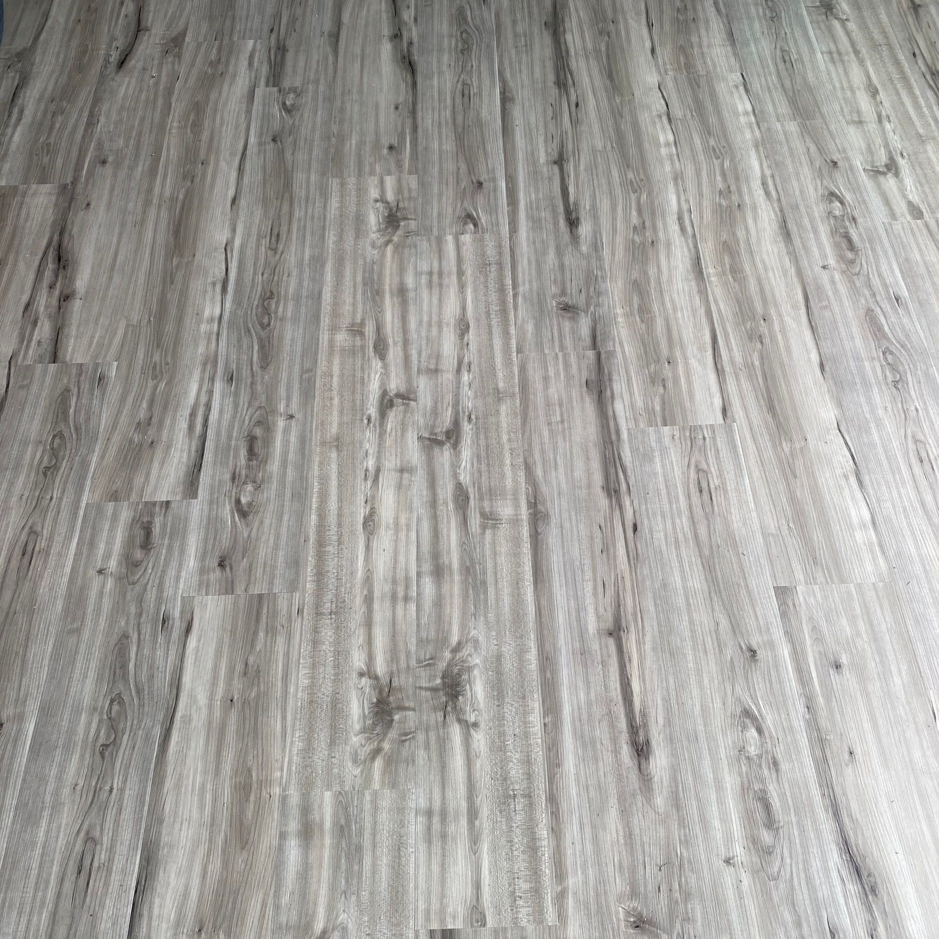 Light gray wood-look floor with vertical grain pattern and some knots.